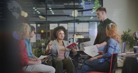 Wheelchair leader facilitating inclusive team meeting in modern office