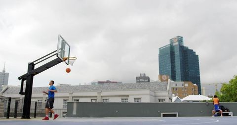 Rooftop basketball player jumping for rim with urban skyline backdrop