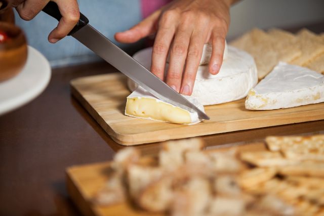 Hand of female staff cutting cheese at counter in market