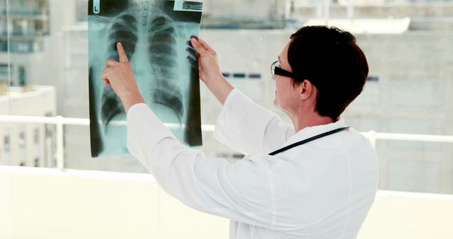 A middle-aged Caucasian male doctor examines an X-ray film, with copy space. His focused analysis suggests he is searching for signs of medical conditions or confirming a diagnosis.