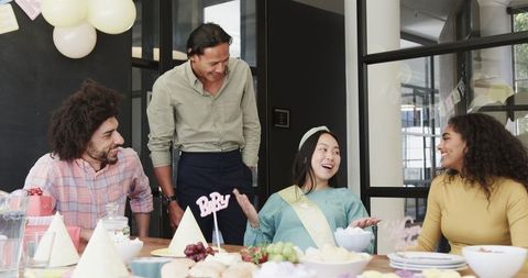 Cheerful office baby shower celebration with multiracial colleagues