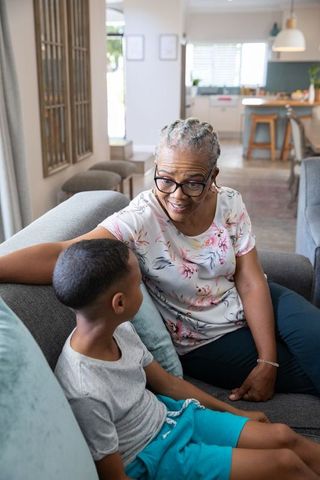 Senior Grandmother Mentoring Young Grandson on Living Room Sofa