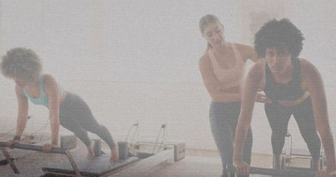 Pilates reformer instructor guiding client through plank posture alignment in studio class