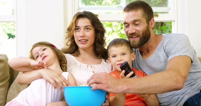 Happy family watching TV at home with popcorn - Download Free Stock Images Pikwizard.com