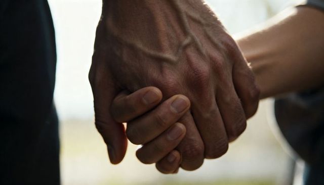 Closeup interlocked hands conveying support and intimacy with soft backlight and bokeh
