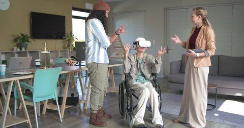 Man in wheelchair testing vr headset while colleagues guiding in modern accessible office