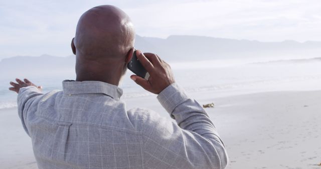 Man Making a Phone Call by the Beach Pointing Out to Sea - Download Free Stock Images Pikwizard.com