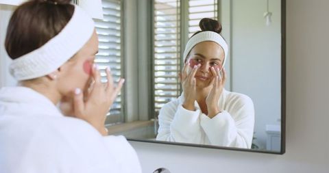 woman applying under-eye patches in minimalist bathroom - Download Free Stock Images Pikwizard.com