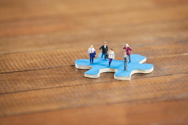 Conceptual image of miniature people on a jigsaw puzzle