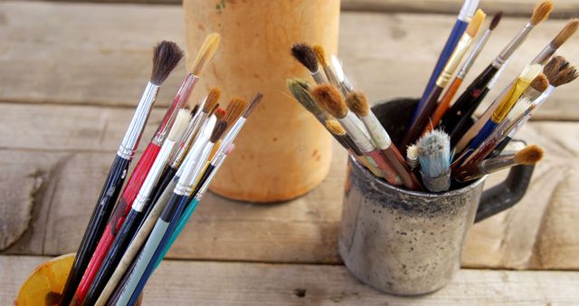 Assorted Paintbrushes in Cups on Wooden Table - Download Free Stock Images Pikwizard.com