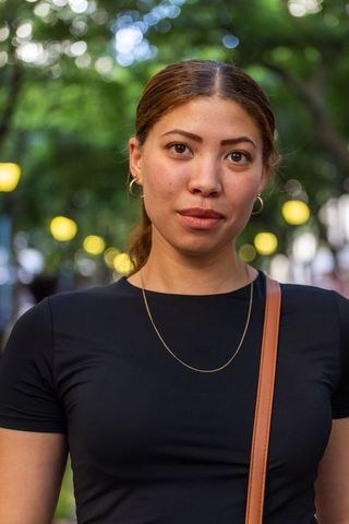 African american woman standing at dusk with bokeh streetlights, black top, gold necklace