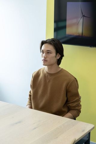 Young professional sitting at light wood table in yellow office with wind turbine art