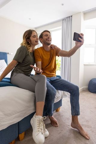 Joyful Couple Taking Selfie on Bed in Bright Modern Bedroom
