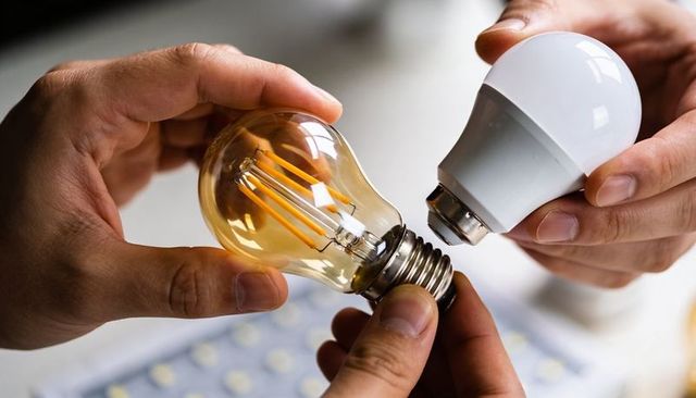 Comparing vintage-style filament led bulb and modern frosted led bulb held by hands