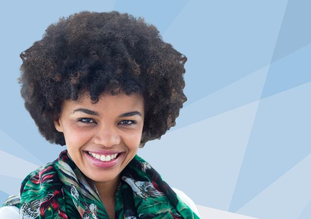 This image features a young African American woman with an afro hairstyle, smiling confidently against a blue geometric background. She is wearing a colorful scarf, adding a touch of fashion and style to the portrait. This image can be used for advertisements, fashion blogs, social media posts, or any content that aims to convey positivity, confidence, and modern style.