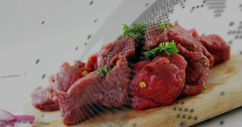 Raw Beef Chunks with Parsley and Cracked Pepper on Cutting Board