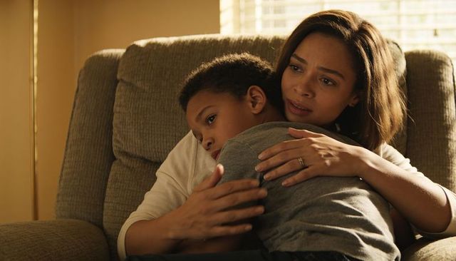 Mother holding son comforting on recliner embracing child during emotional home moment