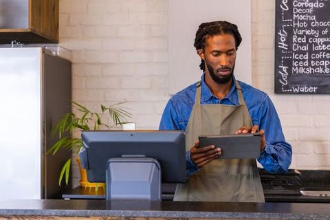 African american barista using tablet at modern cafe counter