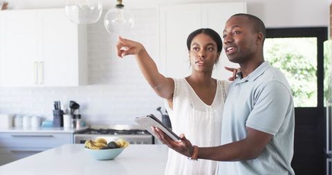 Diverse Couple Discussing Home Renovation with Tablet in Modern Kitchen