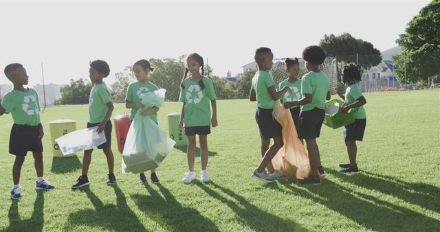 Happy diverse schoolchildren wearing recycle tshirts cleaning sports field at elementary school. School, ecology and education, unaltered.
