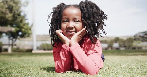 Smiling girl lying on grass in sunny park