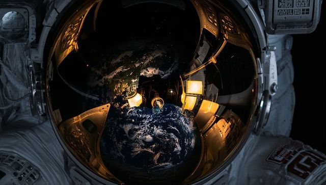 Cosmonaut Helmet Reflecting Earth and Capsule Interior on Gold Visor
