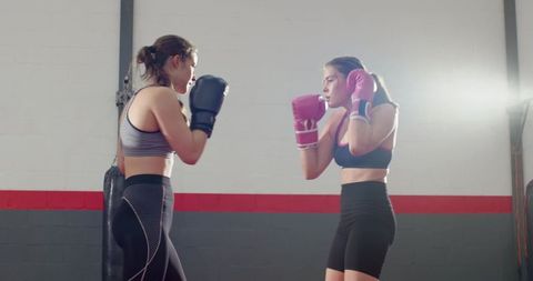 Two Female Boxers Sparring in Industrial Gym Wearing Pink and Black Gloves