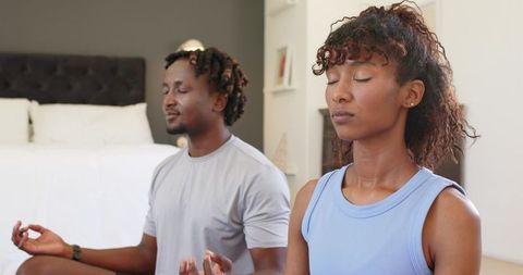 Young couple meditating together in cozy bedroom practicing mindfulness and relaxation