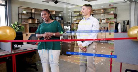 Cutting red ribbon during office launch with diverse team, gold balloons and stock tickers
