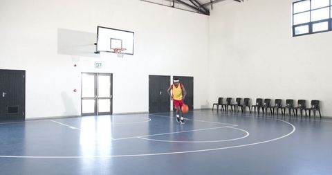 Athlete dribbling basketball indoors on gym court
