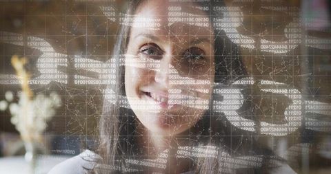 Smiling middle-aged woman gazing through holographic data overlay of code and network