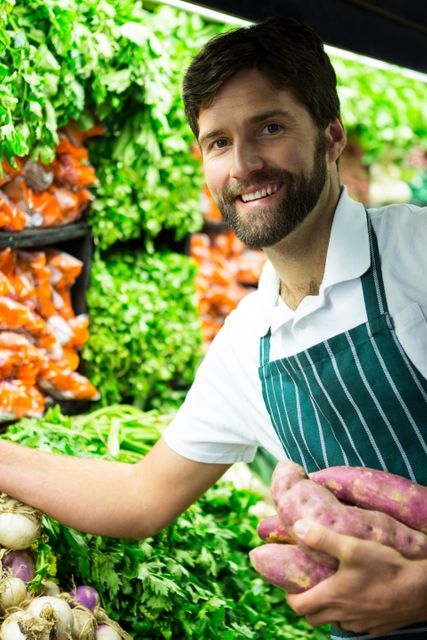 Portrait of male staff arranging vegetables in organic section of supermarket
