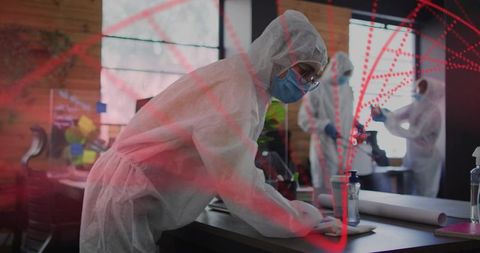Disinfecting office workspace with ppe and fogging team cleaning surfaces during decontamination