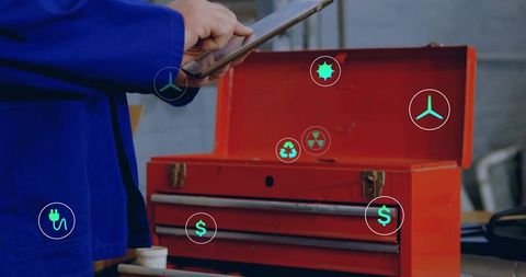 Technician using tablet at workbench over red toolbox with floating energy and finance icons