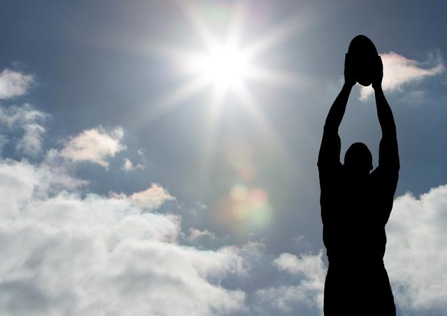 Silhouette of male rugby player catching ball against bright sun and cloudy sky. Ideal for use in sports promotions, fitness campaigns, motivational posters, and outdoor activity advertisements.