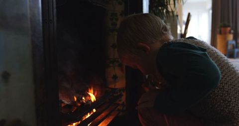 Young Boy Tending Fire in Home Fireplace, Cozy Ambiance