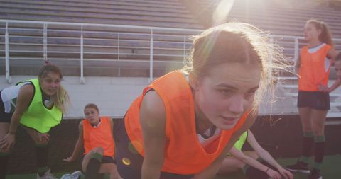Exhausted Female Hockey Team Resting in Sunlit Field
