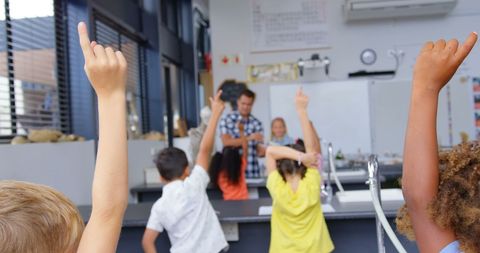 Enthusiastic students raising hands in classroom setting
