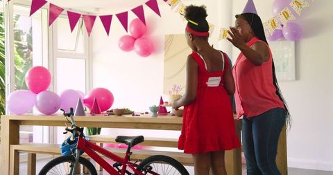 Mother and daughter celebrating birthday at home with decorations and snacks