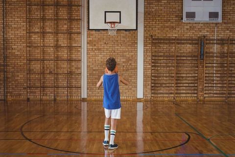 Young Boy Practicing Basketball Shot in Gymnasium
