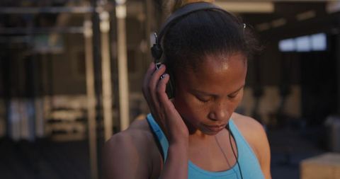 Fit Biracial Woman with Headphones in Gym for Inspiration
