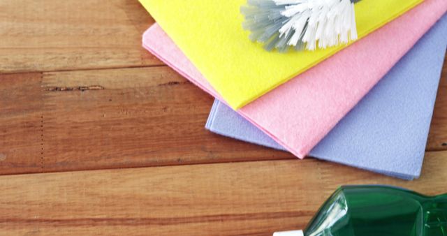 Colorful cleaning supplies include a scrub brush and sponges arranged neatly on a wooden surface. Ideal for adverts on household cleaning products, blogs about cleaning tips, and home hygiene tutorials.