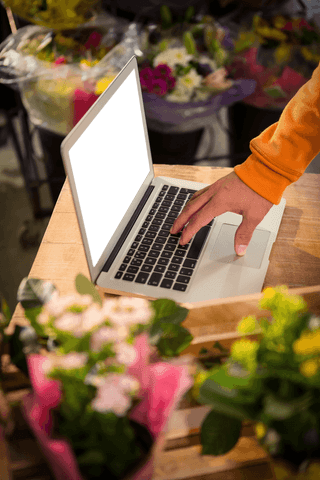 Florist Viewing Laptop Amongst Blooming Flowers Transparent