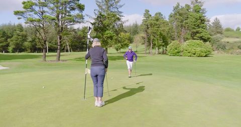 Senior Female Golfers Preparing to Putt on Scenic Golf Course
