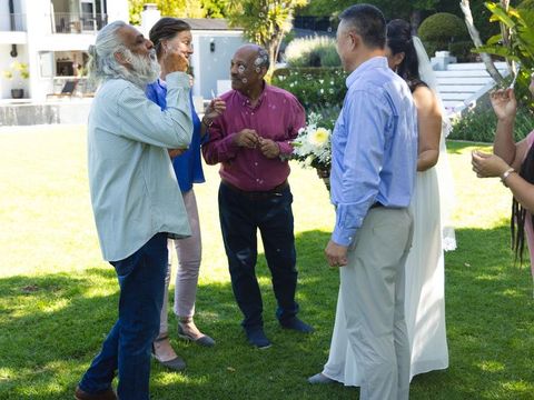 Multigenerational guests blowing bubbles at intimate backyard wedding ceremony