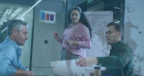 Dynamic team collaborating around office glass board with ui mockups