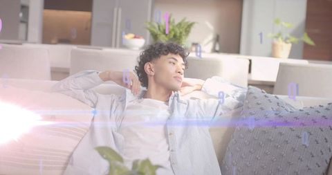 Relaxed young man reclining on modern sofa with sunlight and floating binary digits in minimalist fl