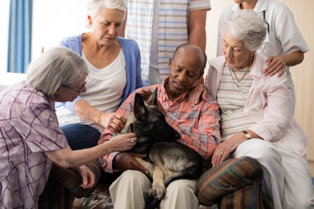 Senior people with doctor stroking dog while sitting on couch at nursing home