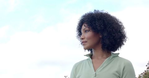 Thoughtful Young Woman with Curly Hair in Outdoor Setting