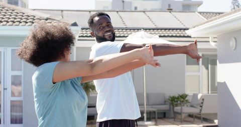 African American Couple Stretching on Sunny Patio for Home Workout and Healthy Lifestyle